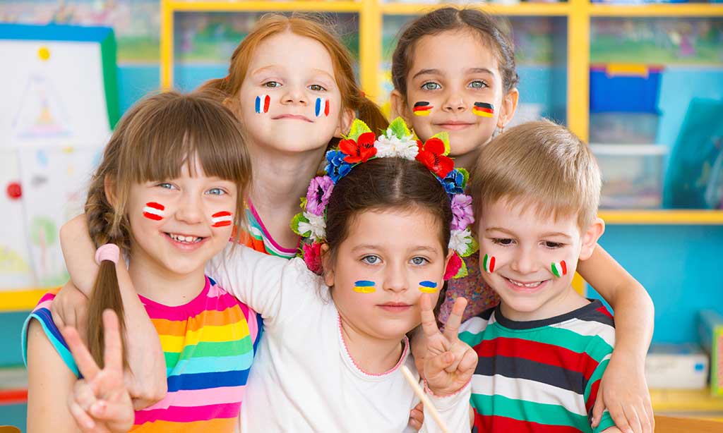 Kinder befinden sich in einer Klasse und haben europäische Flaggen im Gesicht gemalt.